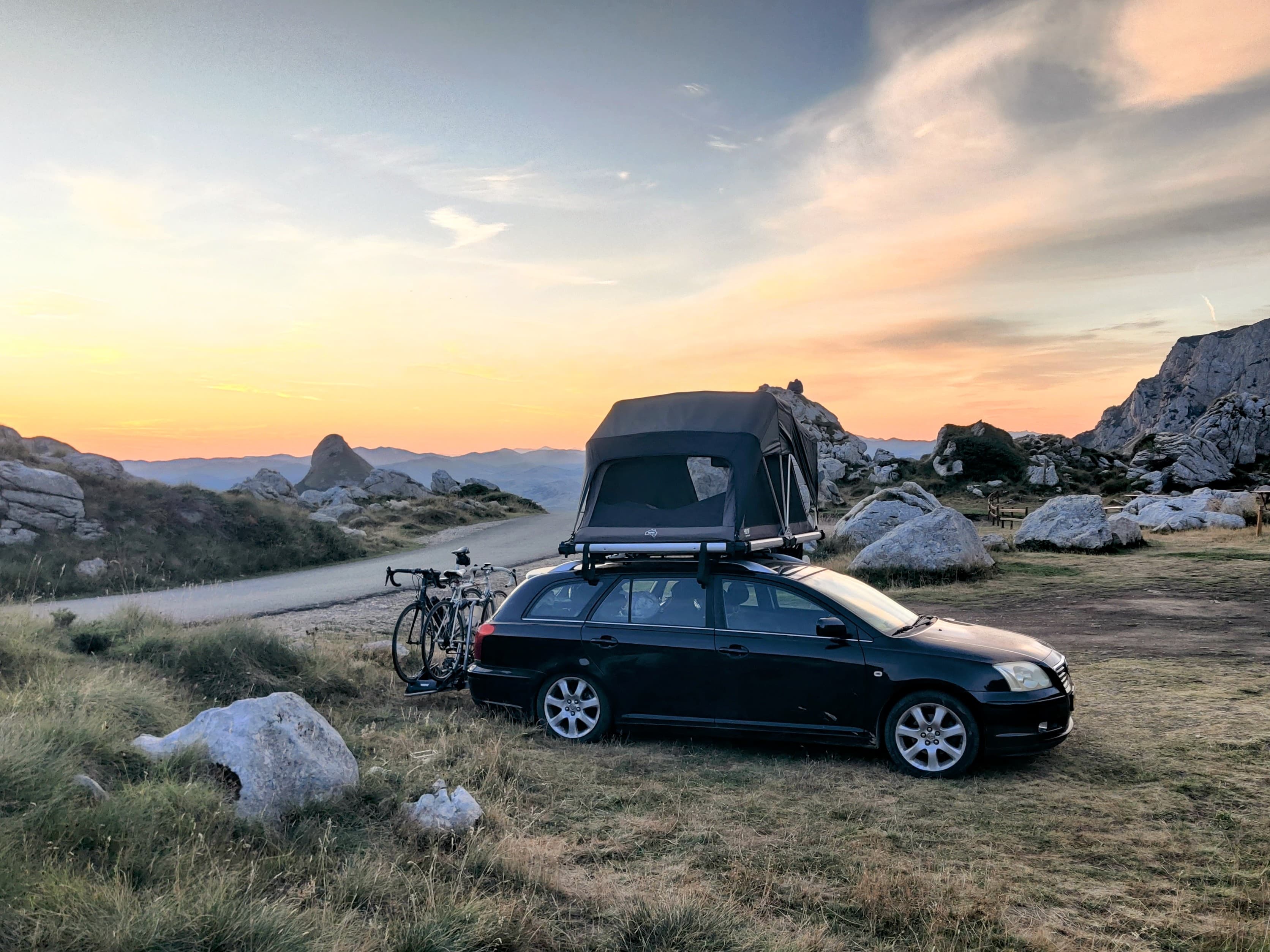 Daktent op een stationwagen in de bergen bij zonsondergang